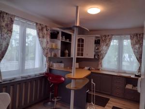 a kitchen with a red stool and some windows at Villa LIKE "garden-grill" in Bardejov