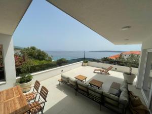 d'une terrasse avec un canapé et des chaises sur un balcon. dans l'établissement Exclusive 2 Bedroom Seafront Suite with jacuzzi, à Zavala