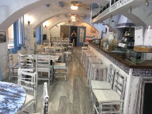 a room with tables and chairs and a person standing at a bar at El Berganti Hotel de Charme in Tossa de Mar