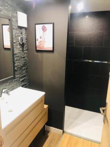 La salle de bains est pourvue d'un lavabo blanc et d'un mur noir. dans l'établissement Le Ristouar Spa forêt et mer, à Quimperlé