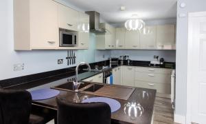 a kitchen with white cabinets and a table with a sink at The Courtyard Lymm in Lymm