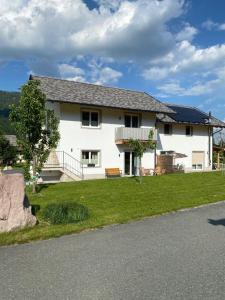 une maison blanche avec une pelouse verte devant elle dans l'établissement Ferienhaus Ute, à Weißbriach