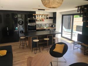 a kitchen with a counter and stools in a room at Le Ristouar Spa forêt et mer in Quimperlé