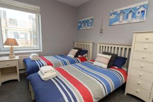 a bedroom with two beds and a desk and a window at Mermaid Apartment - Sea Front Apartment with Views in Saundersfoot