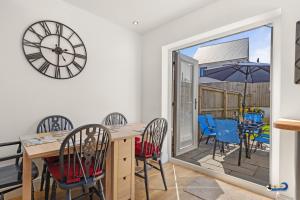 a dining room with a table and chairs and a clock at Park Gardens - Lovely Cottage, Parking, Central Location in Begelly