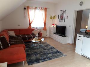 salon z czerwoną kanapą i telewizorem w obiekcie Ferienwohnung Am Sonnenweg w mieście Stanz Im Murztal
