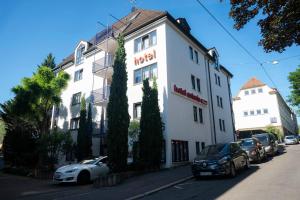 a white building with cars parked in front of it at Hotel Astoria am Urachplatz in Stuttgart