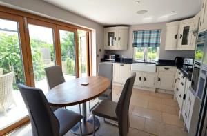 cocina con mesa de madera y sillas en Priory Cottage - Luxury Cottage, Near to Beach, en Saundersfoot