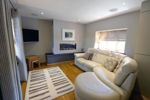 a living room with a white couch and a tv at Priory Cottage - Luxury Cottage, Near to Beach in Saundersfoot