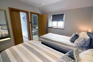 ein Schlafzimmer mit 2 Betten und ein Badezimmer in der Unterkunft Priory Cottage - Luxury Cottage, Near to Beach in Saundersfoot