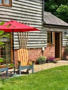 un paraguas rojo sentado junto a una silla y una casa en Archers Cottage en Leominster