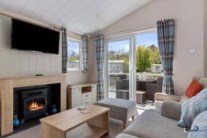 a living room with a fireplace and a tv at St Mary's View - Luxury Lodge, Short Walk to Beach, Parking in Tenby