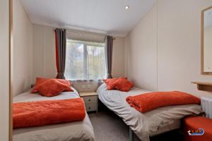 two beds in a room with a window at St Mary's View - Luxury Lodge, Short Walk to Beach, Parking in Tenby