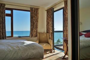 Schlafzimmer mit einem Bett und einem Fenster mit einem Stuhl in der Unterkunft The Cottage - Sea Views, Direct Access to Beach, Pet Friendly in Stepaside