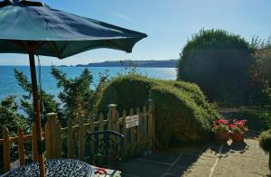 einen Tisch mit einem Regenschirm neben einem Zaun in der Unterkunft The Cottage - Sea Views, Direct Access to Beach, Pet Friendly in Stepaside + 6 Fotos