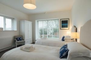 a white bedroom with two beds and a window at The Hawthorns - Large Luxury Cottage, Hot Tub, Sea Views in Saundersfoot