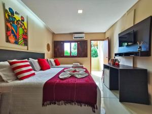 a bedroom with a large bed with red and white pillows at Pousada Casa Kuavá Experience in Maragogi