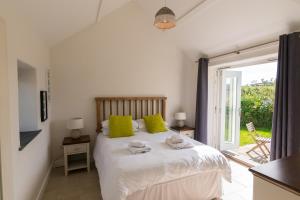 Un dormitorio con una cama con almohadas verdes y una ventana. en The Dairy - Luxury Cottage, Hot Tub and Summer House, Countryside Views, Pet Friendly, en Ludchurch