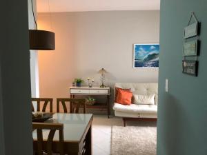 een woonkamer met een witte bank en een tafel bij Apartamento Aconchego - espaço acolhedor e confortável in Ubatuba