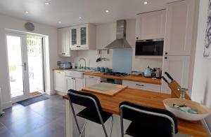 a kitchen with white cabinets and a wooden table at Valley Retreat - Peaceful Location, Walk to Beach, Parking in Saundersfoot