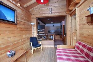 a living room with a couch and a tv on a wooden wall at Appartement à 600m des remontées mécaniques, centre Morzine, chalet les Joux in Morzine