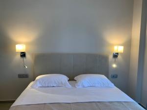 a bed with two white pillows and two lights on the wall at Estia Studios in Stavros