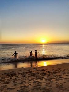 un gruppo di persone che correvano nell'oceano al tramonto di Ótimo apartamento na Praia dos Castelhanos com Wi-Fi a Anchieta