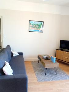 a living room with a blue couch and a coffee table at Les Cocons de Stéphanie avec balcon in Vichy