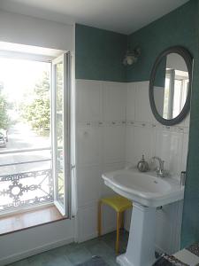 a bathroom with a sink and a mirror and a window at L'Escale in La Jarrie