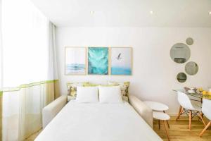 a white bedroom with a bed and a table at Timeless Beach II Apartment in Armação de Pêra