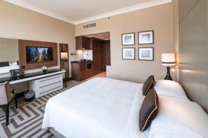 a bedroom with a large white bed and a desk at Al Maha Arjaan by Rotana in Abu Dhabi