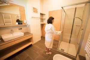 une femme debout dans une salle de bains avec douche dans l'établissement Haus Sonnegg Panoramasuite, à Laion