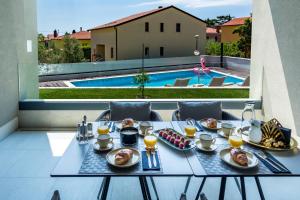 una mesa con comida y vistas a la piscina en Rocca Riviera Umag Luxury Apartments, en Umag