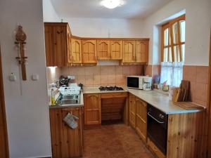 a kitchen with wooden cabinets and a stove top oven at Éva Apartmanház 2 in Csopak