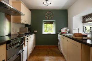 a kitchen with green walls and a clock on the wall at Finest Retreats - Bron Elan in Dolwyddelan