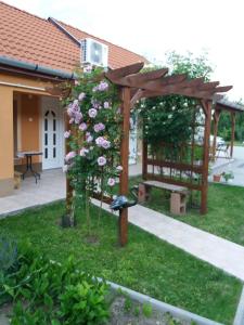 ハイドゥソボスローにあるLevendulás Házの木製のパーゴラとピンクのバラが植えられた庭園