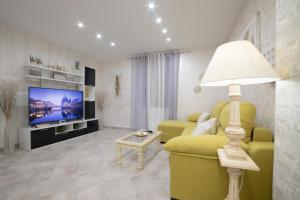 sala de estar con sofá amarillo y TV en APARTAMENTO LA VEGUILLA JUNIOR, en Alhama de Aragón