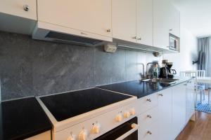 a kitchen with white cabinets and a black counter top at Continental Apartment Hotel Sollentuna in Sollentuna