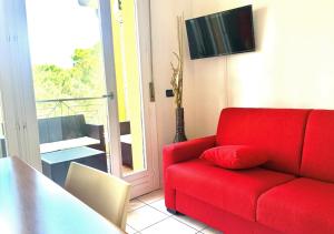 a red couch in a living room with a balcony at Gardalakeapartment a Sirmione in Sirmione