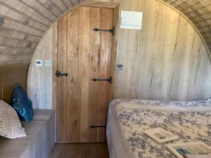 1 dormitorio con 2 camas y pared de madera en Romantic escape luxury Hobbit house with Hot tub! en Sheerness