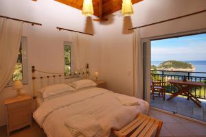 a bedroom with a bed and a balcony with the ocean at Mando Beachfront in Stafylos