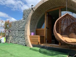 a wicker swing hanging outside of a house at Romantic escape luxury hobbit house with hot tub in Sheerness