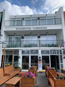 un bâtiment avec des bancs en bois devant lui dans l'établissement Stadshotel Vlissingen, à Flessingue