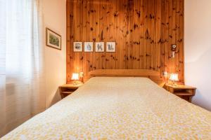 1 Schlafzimmer mit einem Bett mit Holzwänden und 2 Tischen in der Unterkunft Bella Vista 2 in San Zeno di Montagna