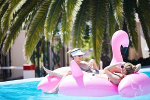 
two girls sitting on top of a pink surfboard in a pool at President Hotel in Cape Town
