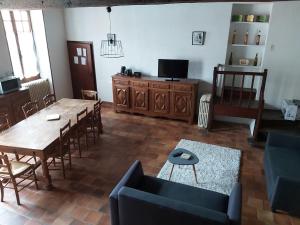 a living room with a table and a couch and a tv at Logis Des Bessons in Migron
