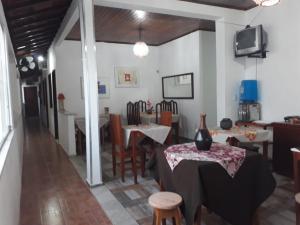 a dining room with tables and chairs and a tv at Pousada Formosa in Porto Seguro