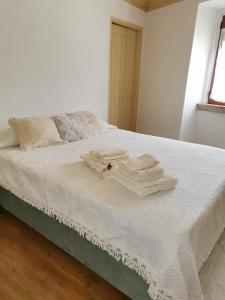 a bed with white sheets and towels on it at A Casinha dos Avós João e Ana in Escalos de Cima