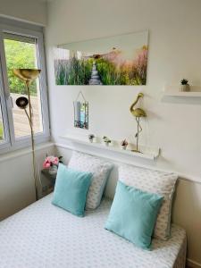 a bedroom with a bed with blue pillows and a window at LE COSY - Lumineux - Proche de Rennes - Spacieux in Liffré