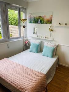 a bedroom with a bed with blue pillows and a window at LE COSY - Lumineux - Proche de Rennes - Spacieux in Liffré